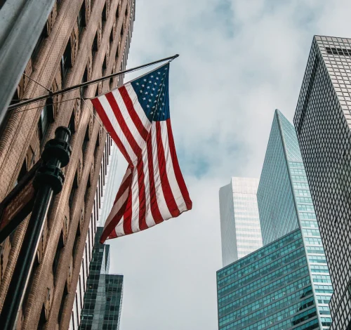 usa-united-states-america-flag-flagpole-near-skyscrapers-cloudy-sky_181624-5054